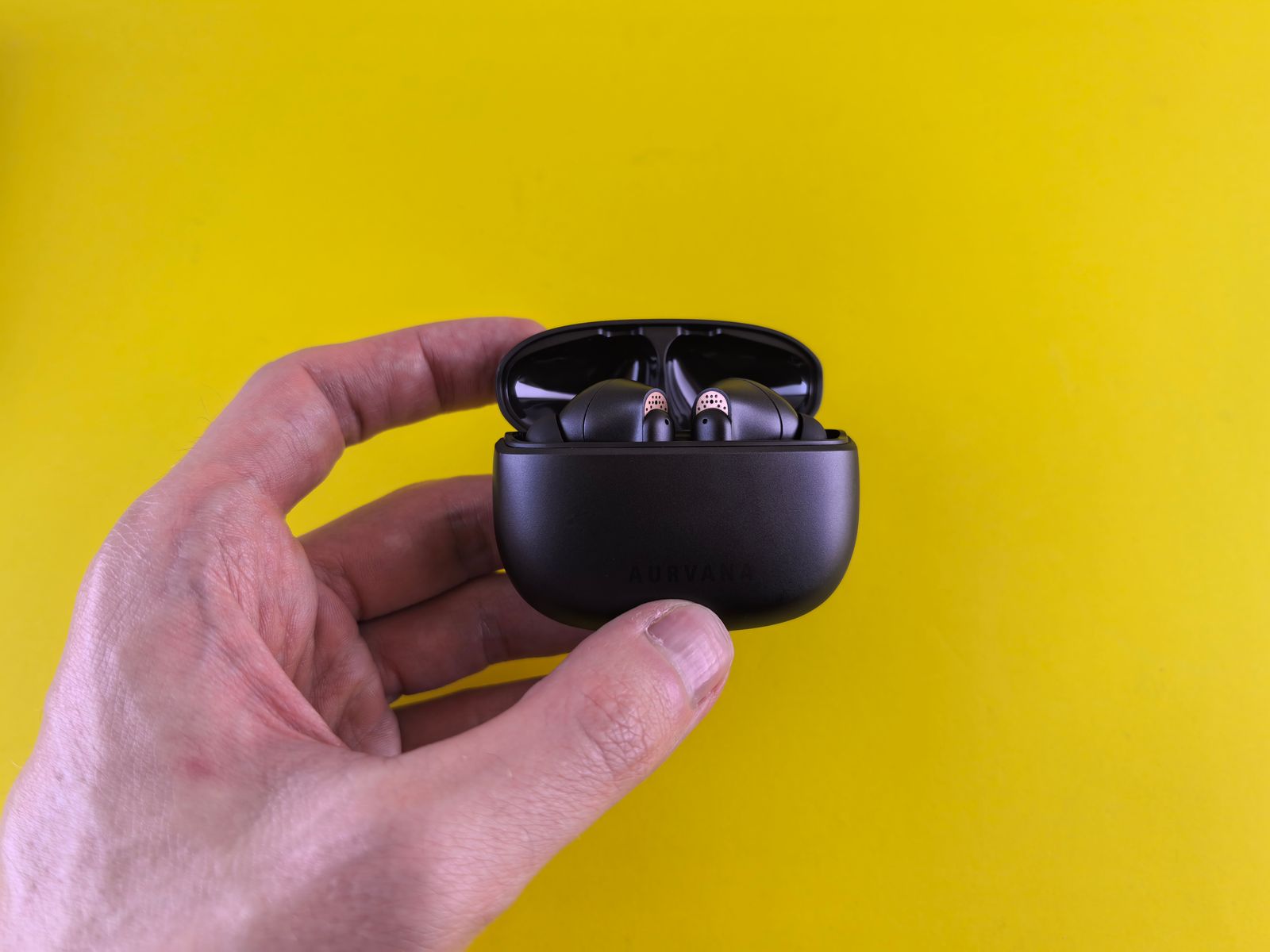 Open wireless earbud charging case held in one hand