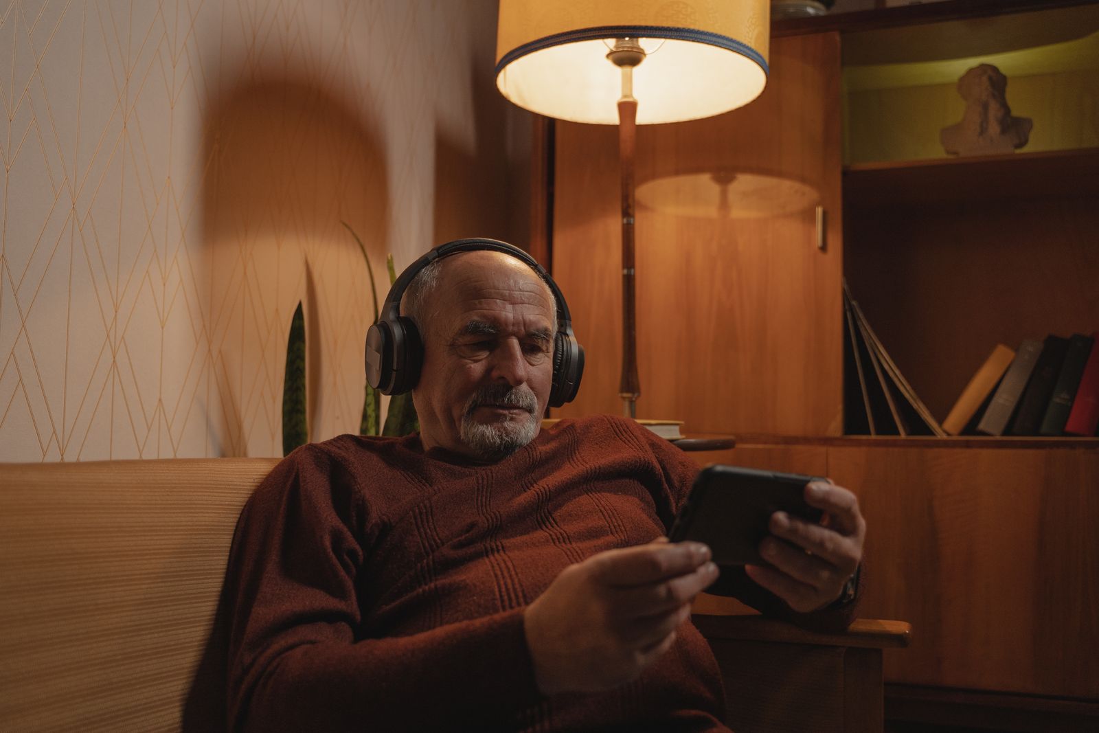 Listener wearing headphones while using a phone at home