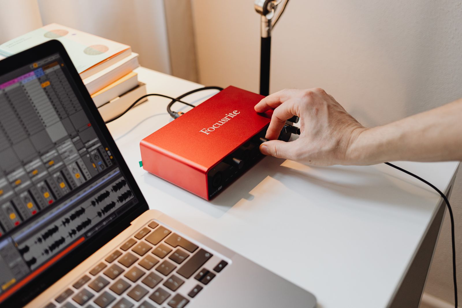 Hand adjusting an audio interface beside a laptop