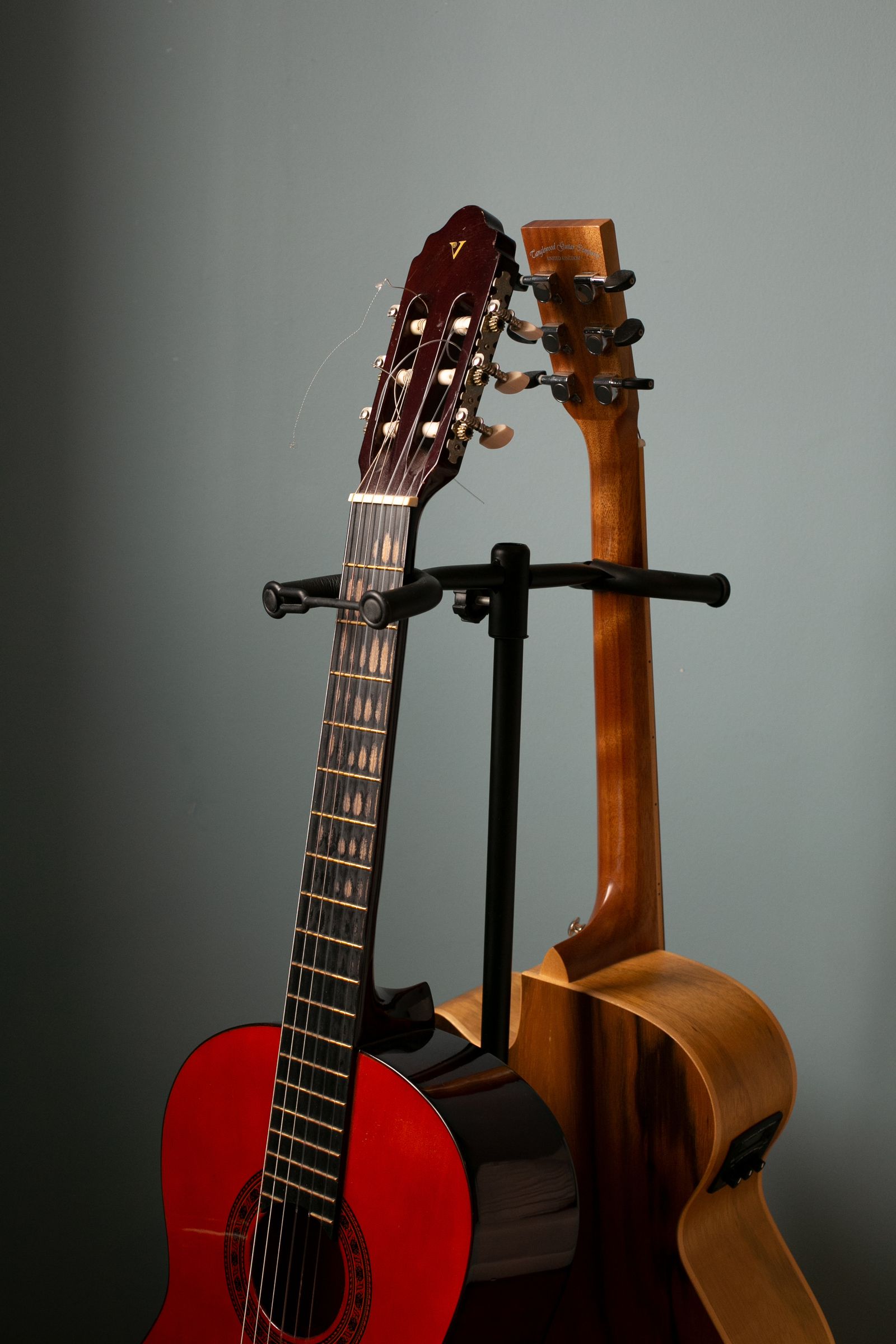 Guitars resting together on a storage stand